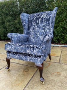 A Parker Knoll winged arm chair recovered with a new cushion, and legs recoloured