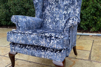 A Parker Knoll winged arm chair recovered with a new cushion, and legs recoloured